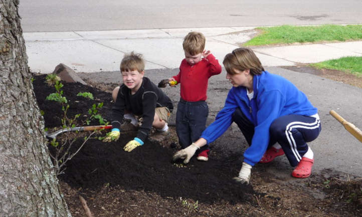 Niños esparciendo abono mientras cultivan un huerto