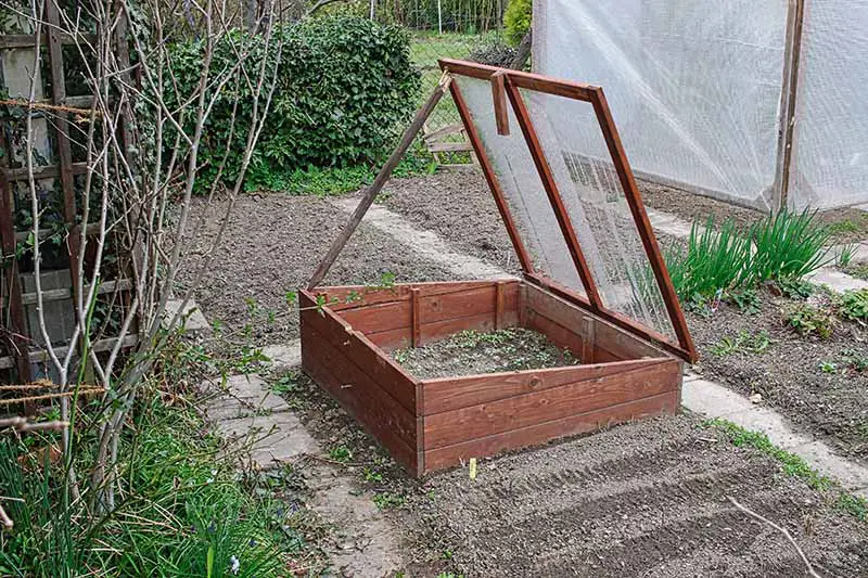 Una imagen horizontal de un marco frío de madera instalado en el jardín para proteger los cultivos del clima frío.