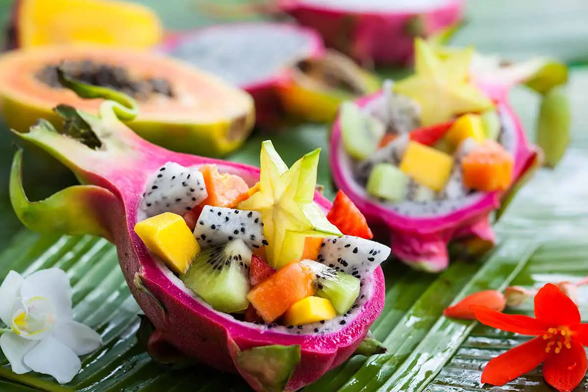 Una imagen horizontal de primer plano de la cáscara de la fruta del dragón que se utiliza como recipiente decorativo para ensaladas de frutas frescas.