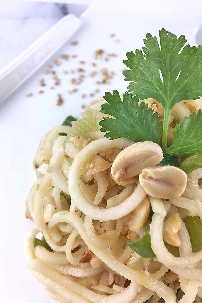 Ensalada de colirrábano en espiral con cacahuetes triturados y guarnición de cilantro.