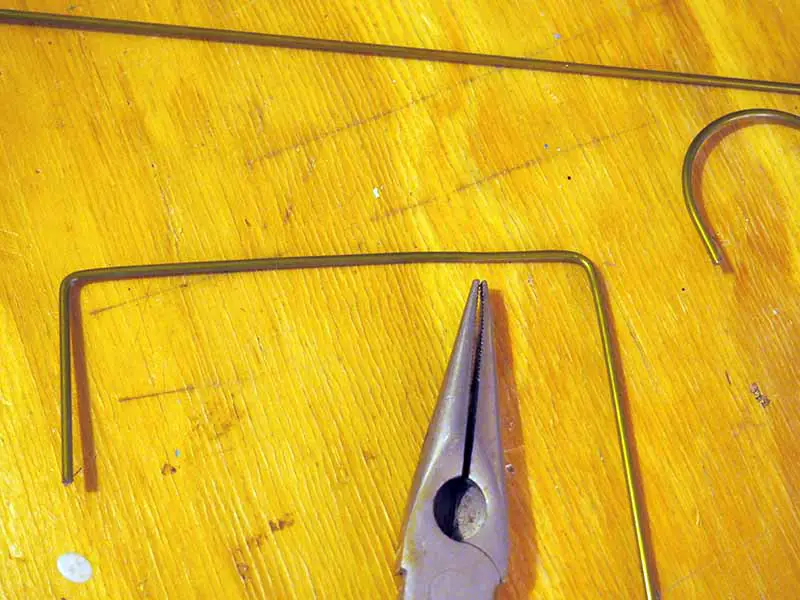 Una imagen horizontal de primer plano de un par de alicates y piezas de metal sobre una superficie de madera.